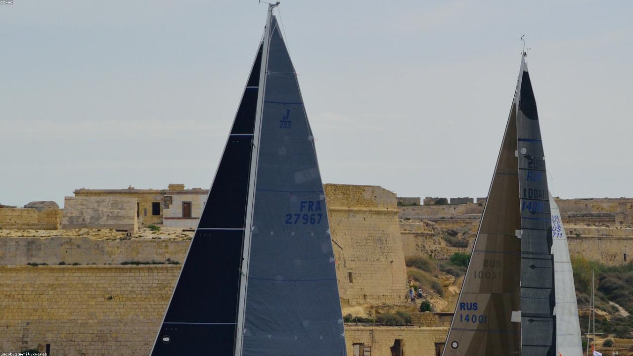 Yachts under sail racing off a harbour